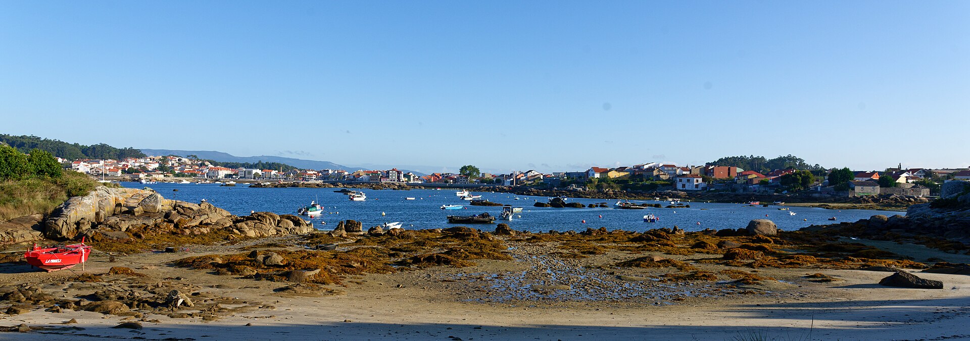 Playa y fondeadero en la Illa de Arousa con lanchas fondeadas en aguas tranquilas
