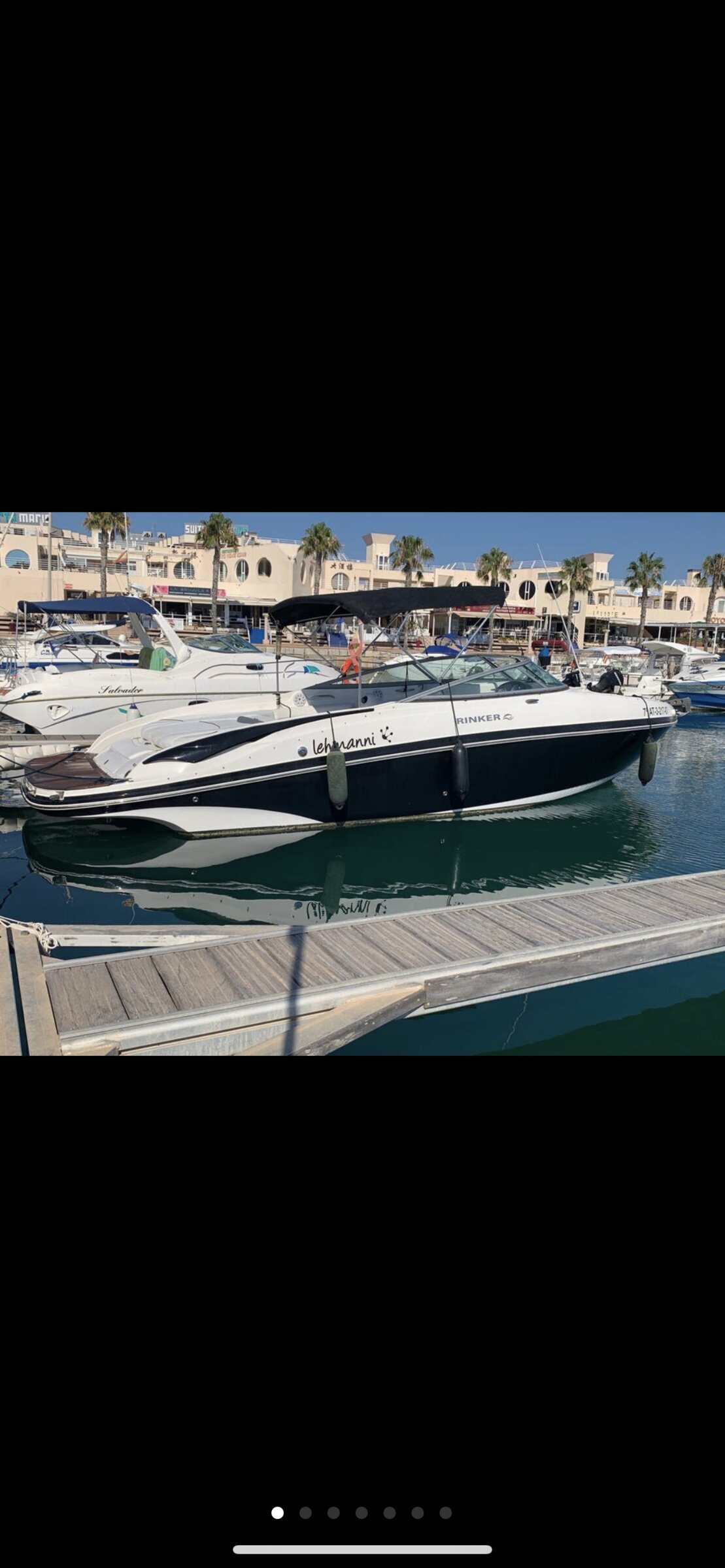 Embarcación Rinker de Arousa Charter atracada en el puerto deportivo de Vilanova de Arousa con palmeras de la marina al fondo